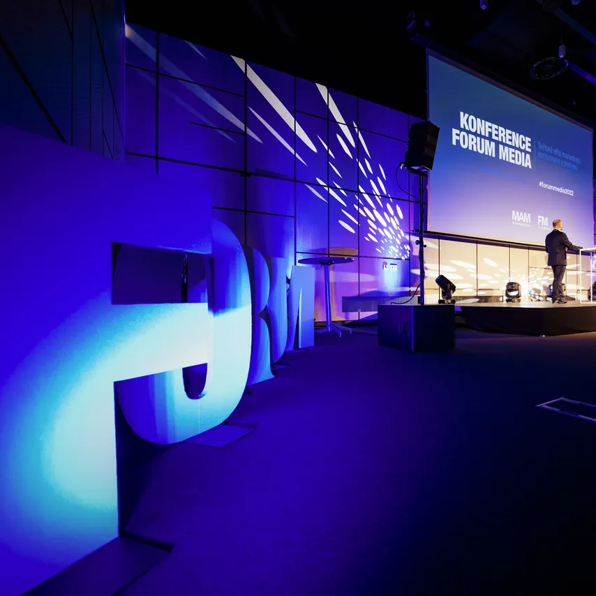Pódium konference Forum Media osvětlené modrými reflektory