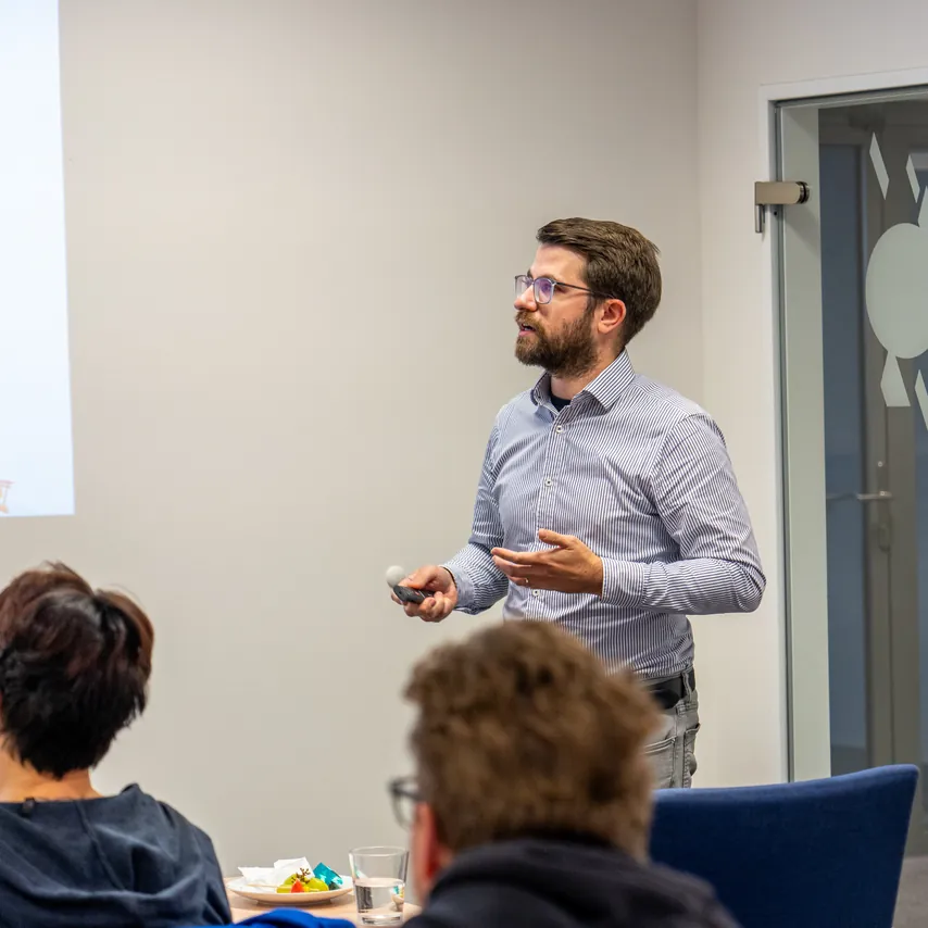 Přednášející před projekcí a účastníci u stolu na snídani ACOMWARE