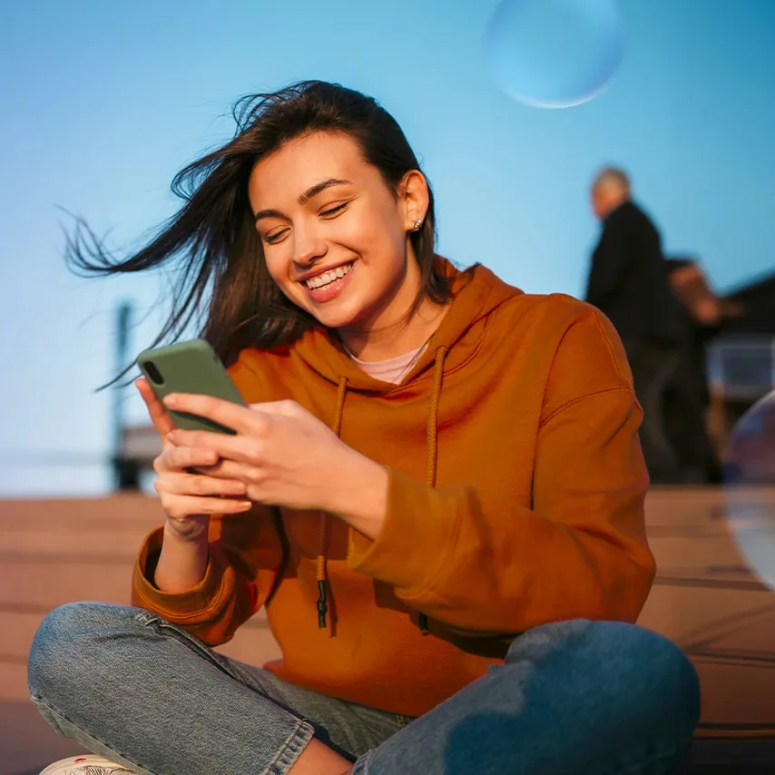 Žena v oranžové mikině si prohlíží telefon – vizuál O2